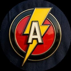 Close-up of a round patch featuring a yellow lightning bolt overlapping a red circle with an A, on dark fabric (The Flash-inspired emblem).