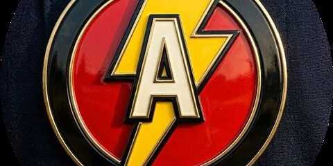 Close-up of a round patch featuring a yellow lightning bolt overlapping a red circle with an A, on dark fabric (The Flash-inspired emblem).